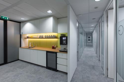 Moderne pantry in een kantoorpand aan het Willemsplein 2 in Den Bosch, met ingebouwde apparatuur en zitgelegenheid.