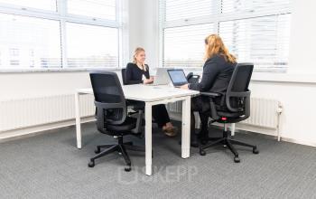 Twee personen aan het werk in een moderne kantoorruimte met veel lichtinval en comfortabel meubilair in kantoorpand op Pettelaarpark 84, Den Bosch.