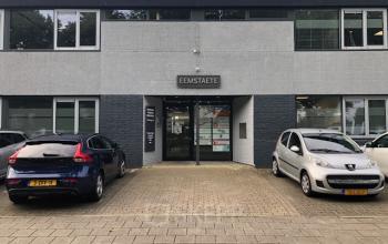 Entree van kantoorpand op Eemweg 1-9, Den Bosch, met Eemstaete bord boven de deur en geparkeerde auto's voor het gebouw.
