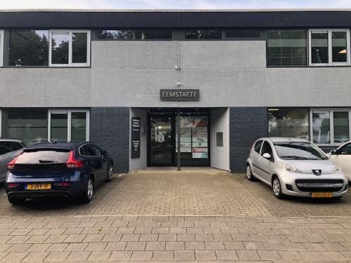 Entree van kantoorpand op Eemweg 1-9, Den Bosch, met Eemstaete bord boven de deur en geparkeerde auto's voor het gebouw.