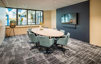 Een stijlvolle kantoorpand in Den Bosch met moderne inrichting, vlakbij grote ramen en een flatscreen aan de muur. Ideaal voor een vergadering of brainstormsessie. Kantoorruimte huren op een centrale locatie.