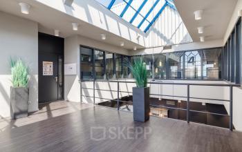 Interieur van een kantoorpand gelegen op Europalaan 4, Den Bosch, met een ruime, openverdieping en veel natuurlijk licht dankzij het glazen dak.