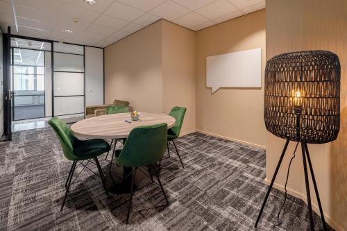 Een kantoorpand in Den Bosch met een vergaderruimte, voorzien van een ronde tafel en groene stoelen. De ruimte nodigt uit tot interactief overleg en is geschikt voor wie kantoorruimte wil huren.
