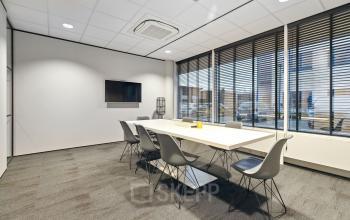 Vergaderruimte in kantoorpand op Europalaan 6, Den Bosch, met moderne vergadertafel, stoelen en televisie. Ideaal voor bedrijven die kantoorruimte willen huren.