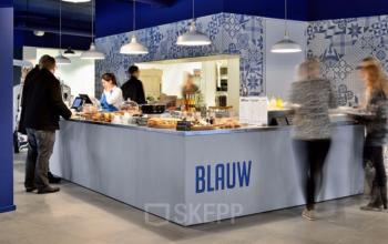 Moderne koffiebar in kantoorpand op Amerikastraat 3, Den Bosch, met enkele mensen die genieten van een pauze. Interessante plek voor kantoorruimte huren.