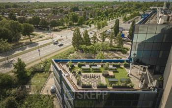 Buitenkant van kantoorpand op Hambakenwetering 1 in Den Bosch met groen dakterras en omliggende infrastructuur.