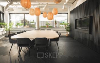 Vergaderruimte in een modern kantoorpand aan de Hambakenwetering 1, Den Bosch met grote tafel en designverlichting, ideaal voor het huren van kantoorruimte.