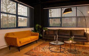 Gezellige kantoorruimte met een bruine en gele bank, ronde tafel en planten. Ideaal voor kantoorruimte huren in Den Bosch aan Bruistensingel 400.