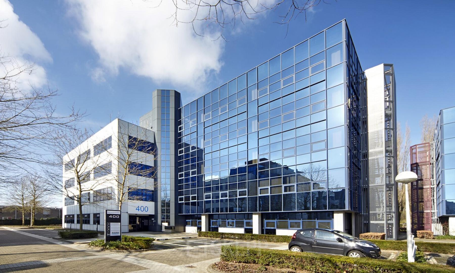 Modern kantoorpand aan de Bruistensingel 400 in Den Bosch, met glazen gevel en parkeerplaatsen voor het huren van kantoorruimte.