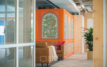 Interieur van kantoor op Hambakenwetering 1-kr, Den Bosch, met kleurrijke muurschildering en comfortabele zithoek. Ideale kantoorruimte huren voor creatieve werkplekken.