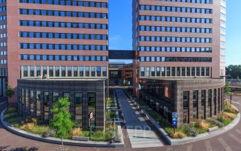 Kantoorpand op Utopialaan 22 in Den Bosch met moderne architectuur. Ideaal voor bedrijven die kantoorruimte willen huren. Het pand toont een zakelijke uitstraling met symmetrisch ontwerp en goed onderhouden omgeving.