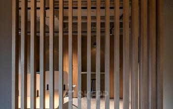 Interieur van een kantoorpand op Pettelaarpark 110, Den Bosch, met houten latwerk en zicht op tafels. Ideale ruimte voor wie kantoorruimte wil huren.