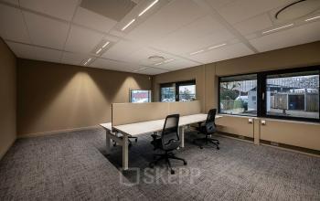 Kantoorruimte huren bij Pettelaarpark 110 in Den Bosch, met strak ingericht interieur, antracietkleurige vloerbedekking, twee bureaus en ergonomische stoelen. Grote ramen voorzien van veel natuurlijk licht.