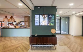Moderne kantoorruimte voor het huren van werkplekken bij Pettelaarpark 110, Den Bosch, met stijlvolle inrichting en prominente TV aan de muur.