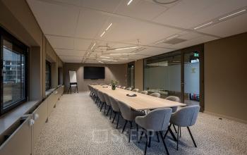 Stijlvolle vergaderruimte in kantoorpand Pettelaarpark 110, Den Bosch, met moderne stoelen en een lange tafel, ideaal voor zakelijke bijeenkomsten en kantoorruimte huren.