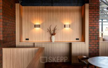 Deze kantoorruimte aan de Hambakenwetering 5 in Den Bosch heeft een warme uitstraling met houten panelen, sfeervolle verlichting en een vaas met decoratie. Ideaal voor creatief gebruik of ontspanning tijdens het werken.