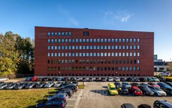 Uitzicht op het kantoorpand aan Hambakenwetering 5, Den Bosch, met meerdere verdiepingen en een grote parkeerplaats voor kantoorruimte huren.