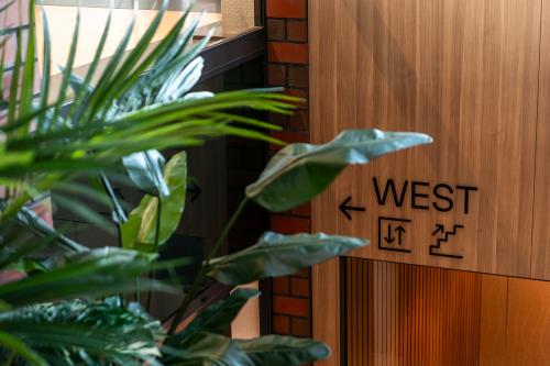 Ingang van een kantoorpand aan Hambakenwetering 5 in Den Bosch met houten afwerking en planten. Bordjes wijzen naar de westelijke vleugel.