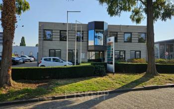 Kantoorpand aan Hambakenwetering 18 in Den Bosch, ideaal voor bedrijven die kantoorruimte willen huren. De moderne gevel is omgeven door groene bomen en biedt parkeergelegenheid.