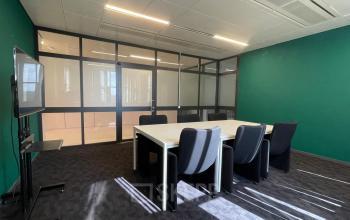 Vergaderruimte in kantoorpand Bruistensingel 500, Den Bosch, met groene muren, glazen wanden, een witte vergadertafel, en zwarte stoelen. Ideaal voor zakelijke bijeenkomsten en kantoorruimte huren.