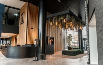 Moderne kantoorruimte op Reitschweg 1 in Den Bosch met sfeervolle verlichting, houten panelen en groene zitplaatsen, ideaal voor verhuur.