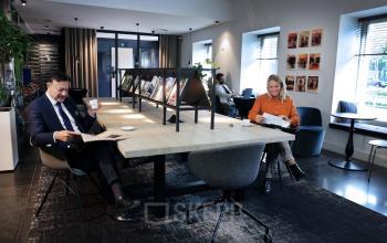 Moderne kantoorruimte op Koninginnegracht 19, Den Haag Centrum. Twee mensen lezen en werken aan een grote tafel.