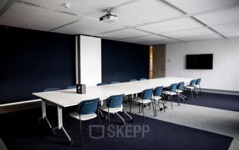 Vergaderruimte in kantoorpand aan Alexanderveld 5-9, Den Haag Centrum. De kamer is ingericht met een lange tafel en comfortabele stoelen, ideaal om kantoorruimte te huren voor zakelijke bijeenkomsten en vergaderingen.