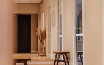 Lichte gang van een kantoorpand op Zeestraat 100, Den Haag Centrum met houten banken en glazen deuren.