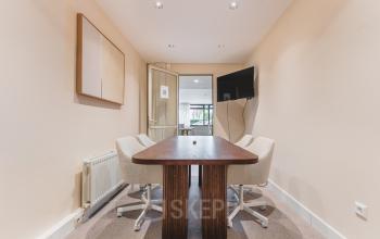 Kantoorruimte huren in Den Haag Centrum aan Zeestraat 100 met meubels zoals een tafel en stoelen in een vergaderruimte.