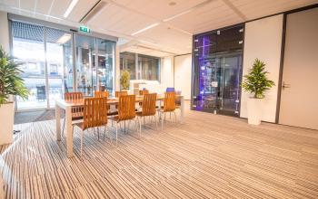 Moderne kantoorruimte in Den Haag Centrum op Koningin Julianaplein 10, met vergadertafel, houten stoelen en planten, ideaal voor kantoorruimte huren.