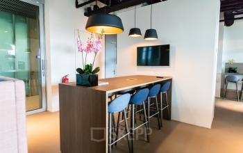 Moderne, gemeubileerde kantoorruimte met hoge tafels en krukken op Koningin Julianaplein 10, Den Haag Centrum, ideaal om te huren voor zakelijke bijeenkomsten.