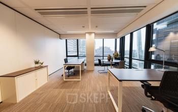Lichte kantoorruimte op Anna van Buerenplein 41 in Den Haag Centrum met grote ramen, bureaus en stoelen, ideaal voor kantoorpand huur. De ruimte is modern gemeubileerd.