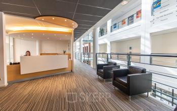 Moderne receptieruimte in kantoorpand op Parkstraat 83 in Den Haag Centrum met een balie, stoelen en een lichte uitstraling.