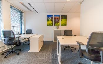 Kantoorruimte huren in modern kantoorpand op Parkstraat 83, Den Haag Centrum. De ruimte heeft voldoende werkplekken met bureaustoelen en natuurlijke lichtinval.