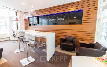 Gezellige business lounge met moderne inrichting op Parkstraat 83 in Den Haag Centrum, ideaal om kantoorruimte te huren. Comfortabele stoelen en hoge tafels bieden een uitnodigende werkruimte.