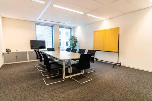 Vergaderruimte te huur in kantoorpand op Parkstraat 83, Den Haag Centrum. De ruimte is functioneel ingericht met een grote tafel, stoelen en een televisie.