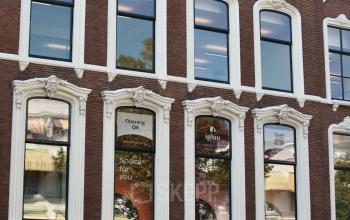 Voorgevel van het kantoorpand op Zeestraat 70 in Den Haag Centrum. Het gebouw heeft hoge ramen, rode bakstenen muren en witte raamkozijnen, met advertenties voor kantoorruimte huren.