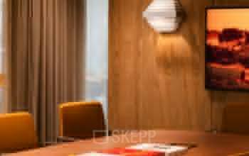 Vergaderruimte in kantoorpand Zeestraat 70, Den Haag Centrum met houten wanden, moderne verlichting en gele stoelen rond een grote tafel.