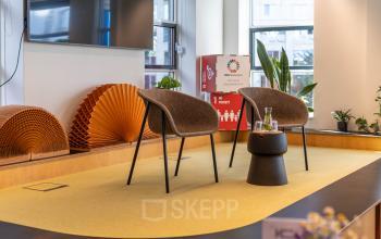 Moderne kantoorruimte te huur op Fluwelen Burgwal 58 in Den Haag Centrum, met een podium, stoelen, en planten op de achtergrond.