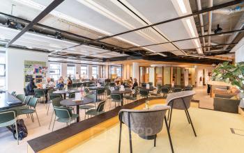 Lichte kantoorruimte in Den Haag Centrum met moderne inrichting en werkende mensen aan tafels. Ideaal voor het huren van een dynamische werkplek.