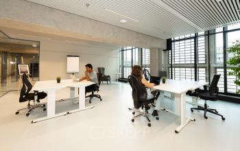 Moderne kantoorruimte huren in Den Haag Centrum aan de Waldopstraat 5, met strakke bureaus en ergonomische stoelen, waar zakelijke professionals gefocust werken in een lichte omgeving met grote ramen.
