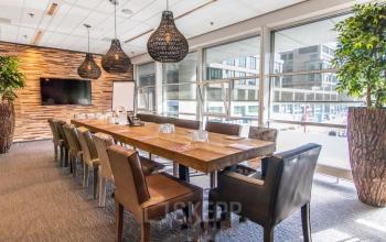 Vergaderruimte in kantoorpand op Kalvermarkt 53, Den Haag Centrum met lange tafel, lederen stoelen, grote ramen en moderne verlichting. Perfect voor kantoorruimte huren.