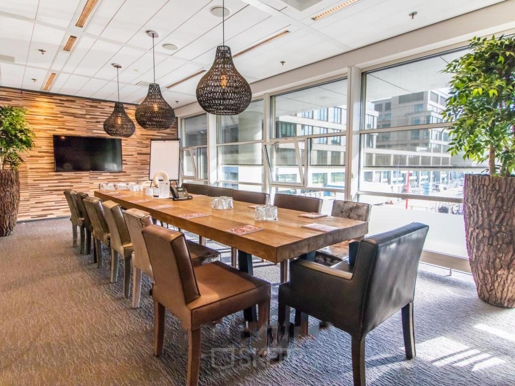 Vergaderruimte in kantoorpand op Kalvermarkt 53, Den Haag Centrum met lange tafel, lederen stoelen, grote ramen en moderne verlichting. Perfect voor kantoorruimte huren.