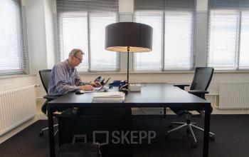 Moderne kantoorruimte op Platinaweg 25, Den Haag Escamp met een werkende man aan een bureau, met lamp en stoelen, ideaal voor kantoren en kantoorruimte huren.