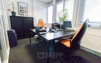Een gemeubileerd kantoor op Platinaweg 25, Den Haag Escamp, met twee bureaus, computerschermen en oranje accenten. Ideaal voor wie kantoorruimte wil huren in een kantoorpand.