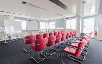 Bij Platinaweg 25 in Den Haag Escamp vind je deze vergaderruimte met rode stoelen en presentatieapparatuur, ideaal voor wie een kantoorruimte wil huren voor bijeenkomsten.