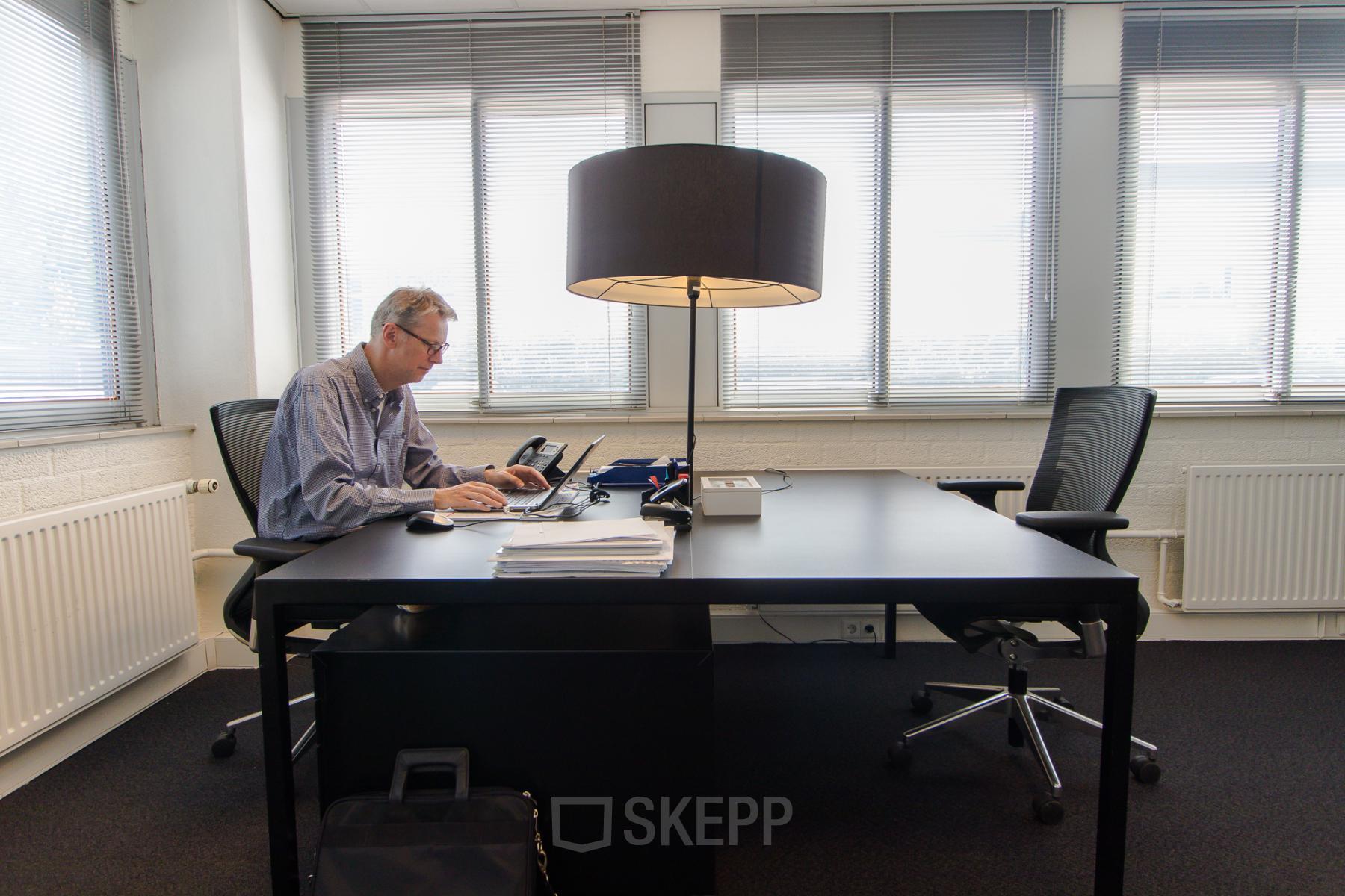 Moderne kantoorruimte op Platinaweg 25, Den Haag Escamp met een werkende man aan een bureau, met lamp en stoelen, ideaal voor kantoren en kantoorruimte huren.