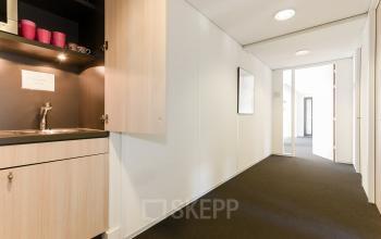 Entree van een kantoorpand aan de Bezuidenhoutseweg 161, Den Haag Haagse Hout. De ruimte is voorzien van een kleine pantry met kasten en een kraan. Ideaal voor kantoorruimte huren.