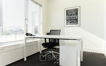 Lichte kantoorkamer op Bezuidenhoutseweg 161, Den Haag, met een modern bureau, ergonomische stoel en kunst aan de muur. Ideale ruimte voor kantoorruimte huren in Haagse Hout.