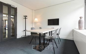 Kantoorruimte met moderne inrichting op Bezuidenhoutseweg 161, Den Haag Haagse Hout. Een lichte vergaderruimte met een tafel, vier stoelen en een muurtelevisie. Ideaal voor professionele bijeenkomsten en kantoorruimte huren.